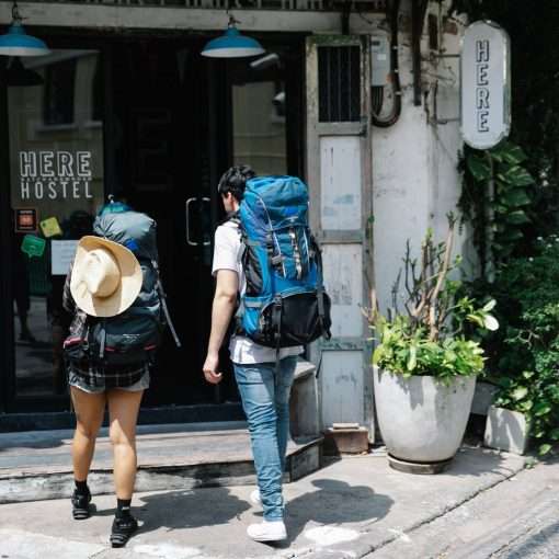 unrecognizable couple of travellers with backpacks entering hotel