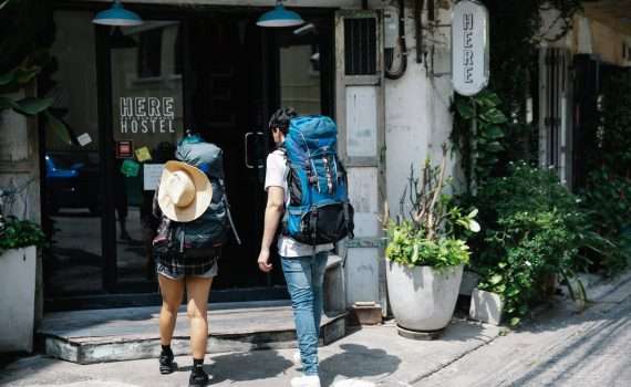 unrecognizable couple of travellers with backpacks entering hotel