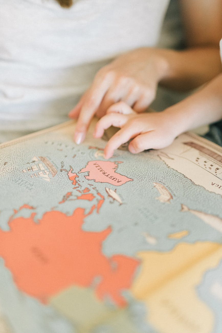 a person and a child pointing at australia on a map