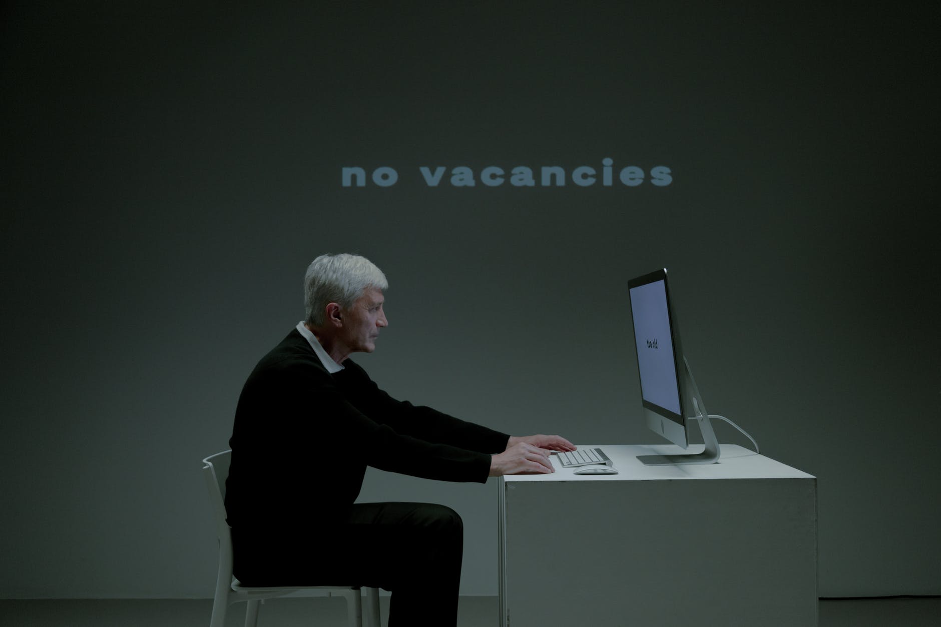 senior adult man sitting in front of pc and writing on keyboard