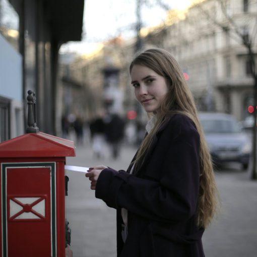 woman wearing violet coat while standing near mailbox
